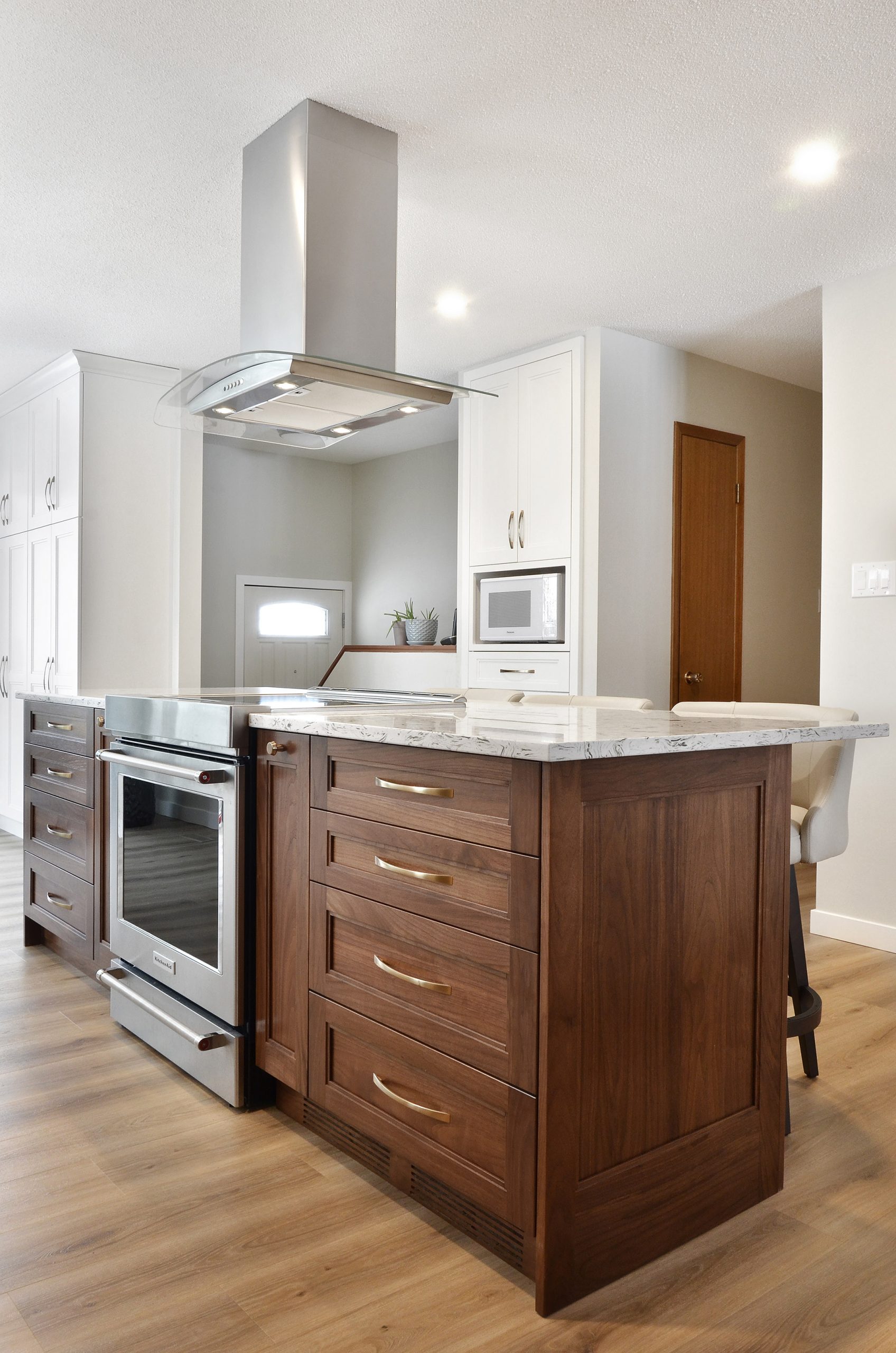 Winnipeg renovations modern kitchen sleek white cabinets white marble countertop wood drawers over range vent